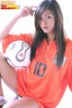 Seated with ball long hair over orange football shirt